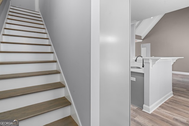 stairs featuring sink and wood-type flooring