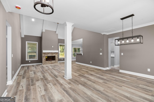 unfurnished living room featuring vaulted ceiling, a brick fireplace, and light hardwood / wood-style flooring