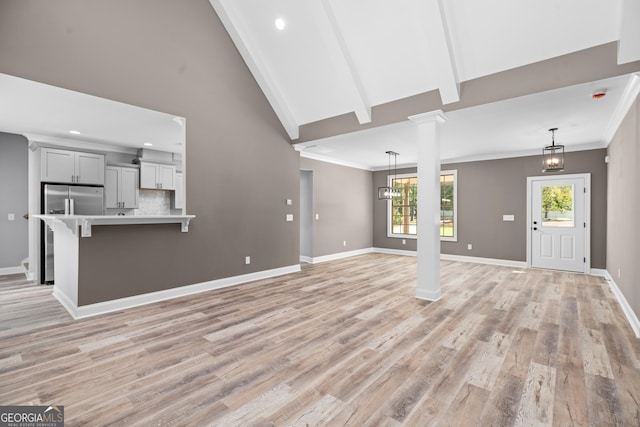 unfurnished living room with ornate columns, a chandelier, light hardwood / wood-style floors, and beam ceiling