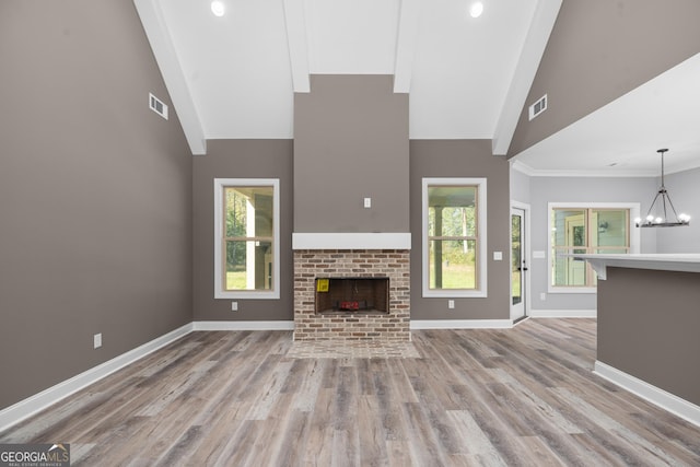 unfurnished living room with high vaulted ceiling, light hardwood / wood-style flooring, a notable chandelier, and a fireplace