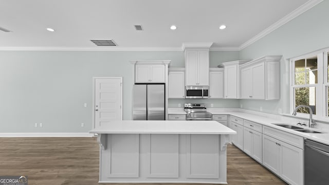 kitchen featuring appliances with stainless steel finishes, sink, white cabinetry, and a center island