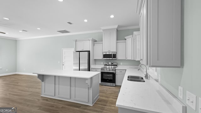 kitchen featuring stainless steel appliances, dark hardwood / wood-style floors, a center island, ornamental molding, and sink