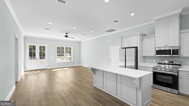 kitchen featuring appliances with stainless steel finishes, a kitchen island, french doors, light hardwood / wood-style floors, and ceiling fan