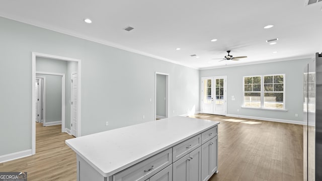 kitchen featuring a center island, gray cabinets, light wood-type flooring, ceiling fan, and crown molding