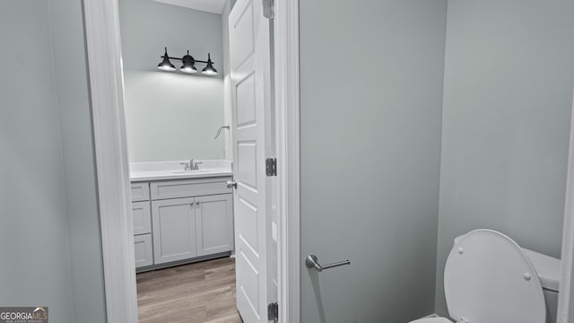 bathroom with toilet, vanity, and hardwood / wood-style flooring