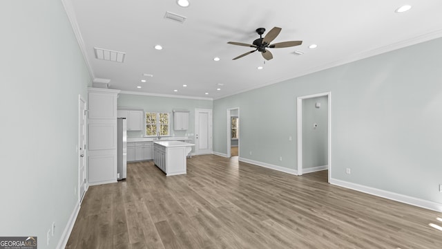 unfurnished living room with ceiling fan, light wood-type flooring, sink, and crown molding