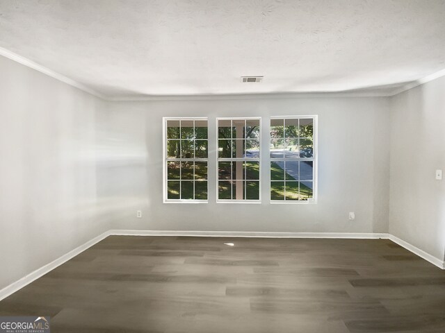 empty room with a wealth of natural light, ornamental molding, and dark wood-type flooring