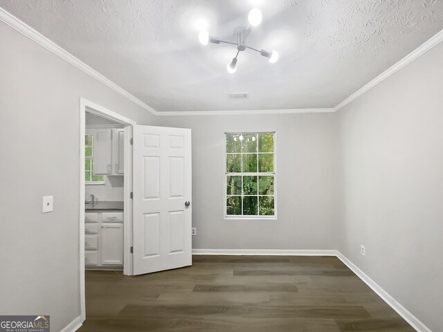 unfurnished bedroom with ornamental molding, multiple windows, a textured ceiling, and dark wood-type flooring