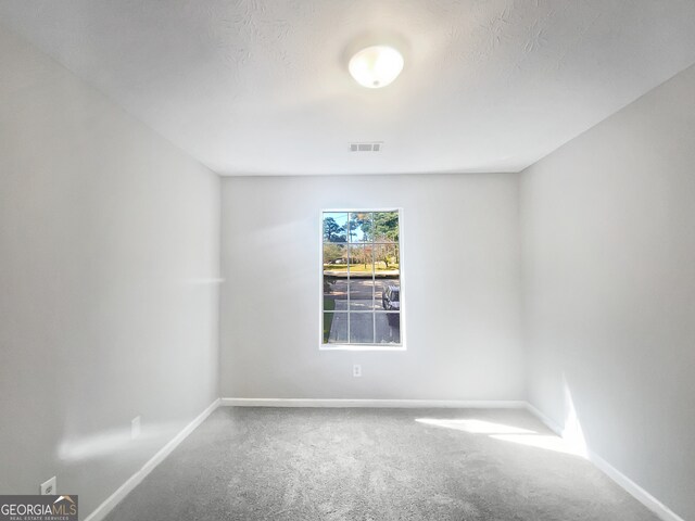 carpeted empty room with a textured ceiling