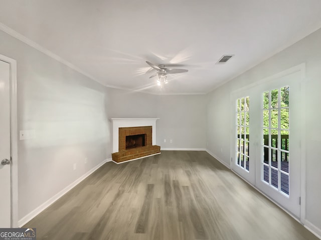 unfurnished living room featuring ceiling fan, crown molding, a brick fireplace, and hardwood / wood-style floors