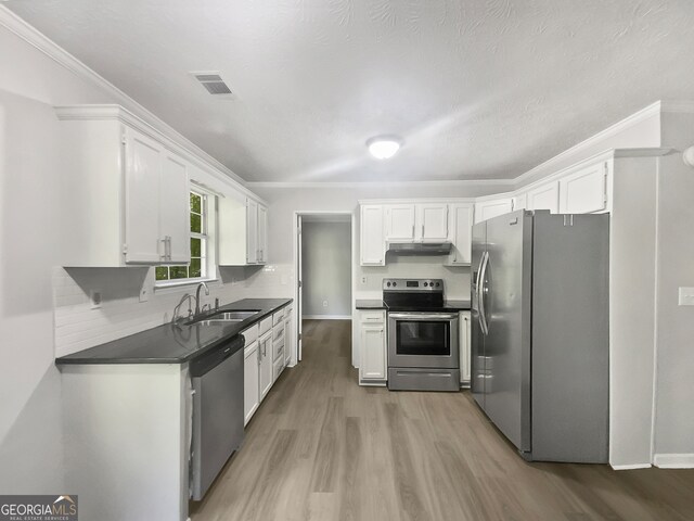 kitchen featuring appliances with stainless steel finishes, white cabinetry, hardwood / wood-style flooring, and sink