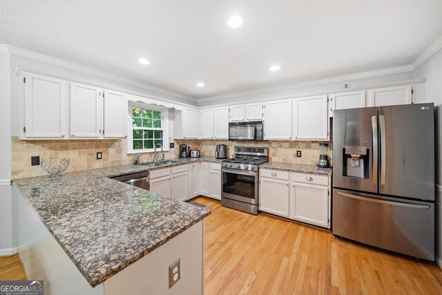 kitchen featuring kitchen peninsula, white cabinetry, sink, and appliances with stainless steel finishes