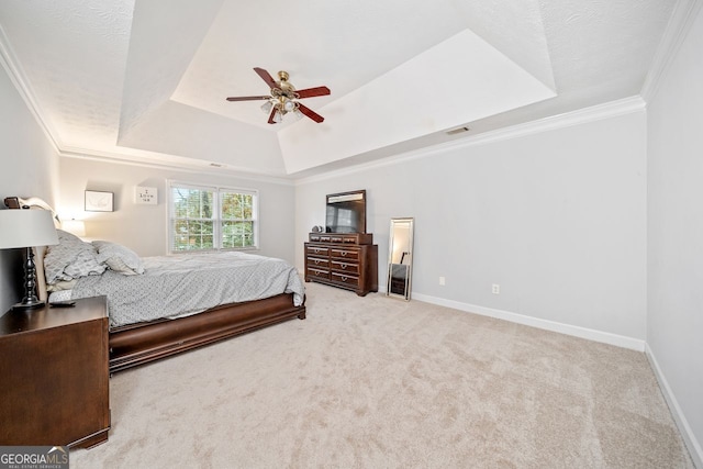 carpeted bedroom featuring ceiling fan, crown molding, and a tray ceiling