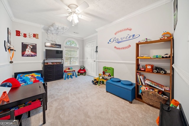 playroom with carpet flooring, ceiling fan, a textured ceiling, and ornamental molding