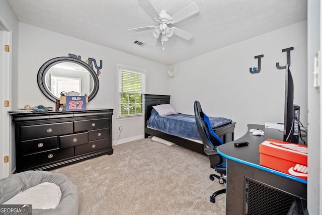 bedroom featuring a textured ceiling, light colored carpet, and ceiling fan