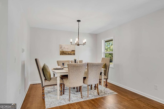 dining area with dark wood-type flooring and a notable chandelier