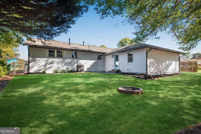 rear view of property featuring a fire pit and a yard