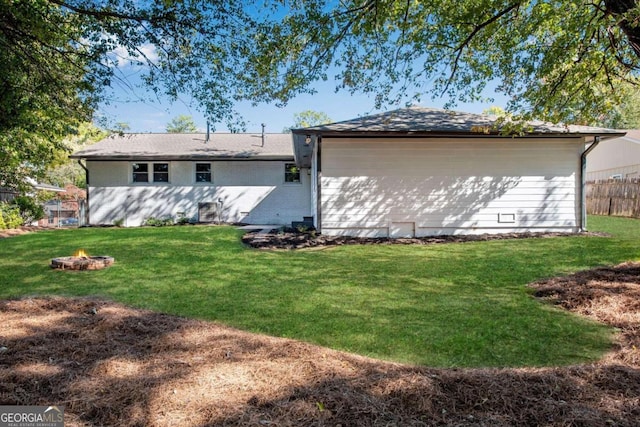 back of property featuring an outdoor fire pit and a lawn