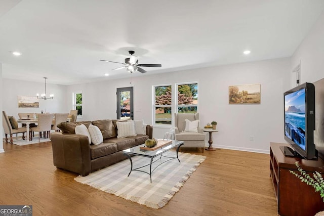 living room with light hardwood / wood-style flooring and ceiling fan with notable chandelier