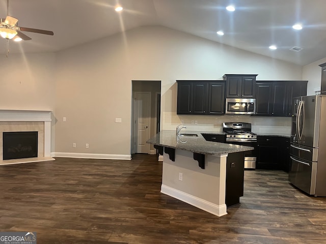 kitchen with appliances with stainless steel finishes, sink, a breakfast bar, and dark hardwood / wood-style flooring