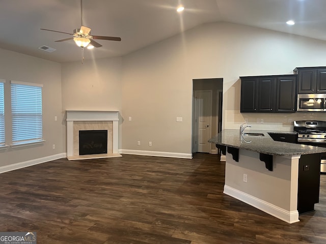 kitchen with sink, a breakfast bar, appliances with stainless steel finishes, dark stone countertops, and dark hardwood / wood-style flooring