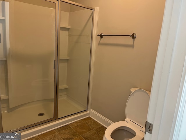 bathroom with tile patterned flooring, toilet, and a shower with shower door