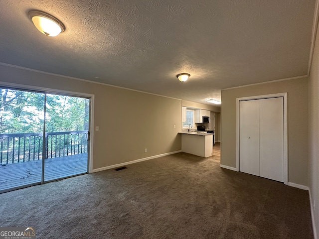 unfurnished living room featuring a textured ceiling, ornamental molding, and dark carpet