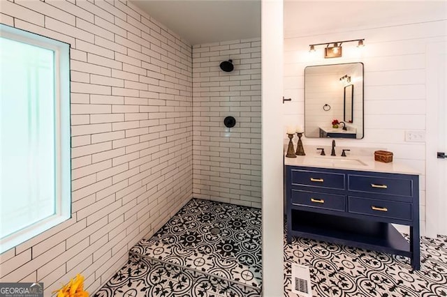 bathroom with vanity, tiled shower, and tile patterned flooring