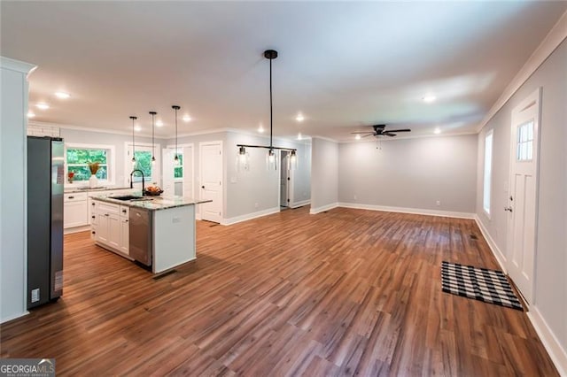 kitchen featuring appliances with stainless steel finishes, an island with sink, pendant lighting, white cabinets, and hardwood / wood-style flooring