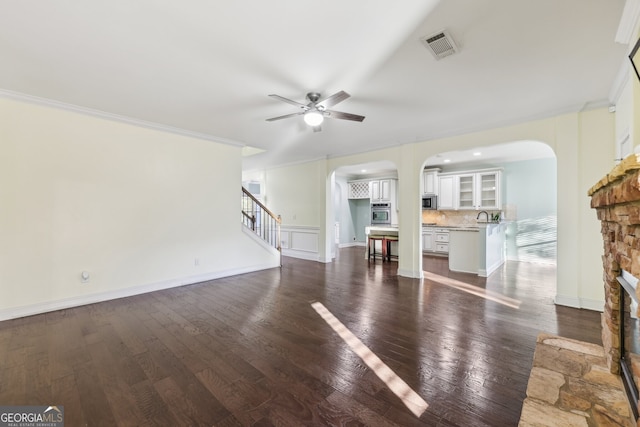 unfurnished living room with dark wood-type flooring, ceiling fan, sink, and crown molding