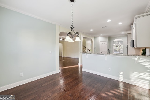 kitchen featuring dark hardwood / wood-style flooring, white cabinets, kitchen peninsula, hanging light fixtures, and light stone countertops