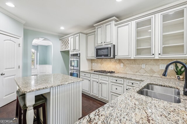 kitchen featuring a kitchen breakfast bar, appliances with stainless steel finishes, sink, and light stone countertops