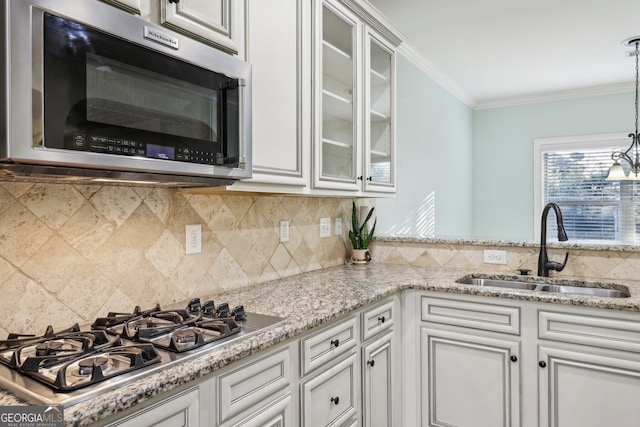 kitchen with stainless steel appliances, decorative backsplash, sink, pendant lighting, and white cabinetry