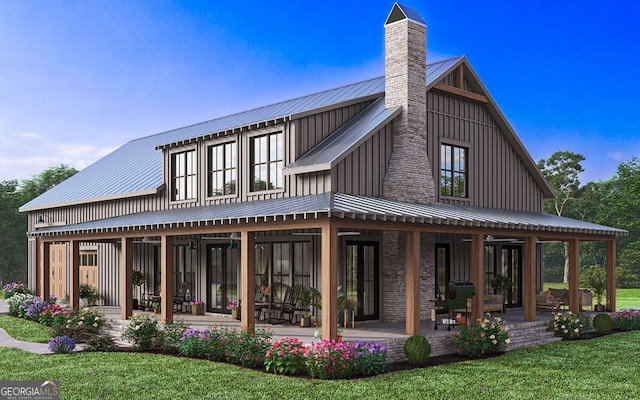 back of house with metal roof, a lawn, board and batten siding, a standing seam roof, and a chimney