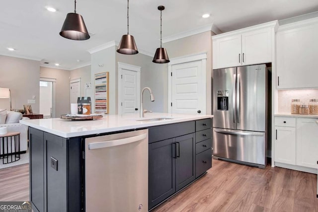 kitchen featuring white cabinets, an island with sink, appliances with stainless steel finishes, pendant lighting, and sink