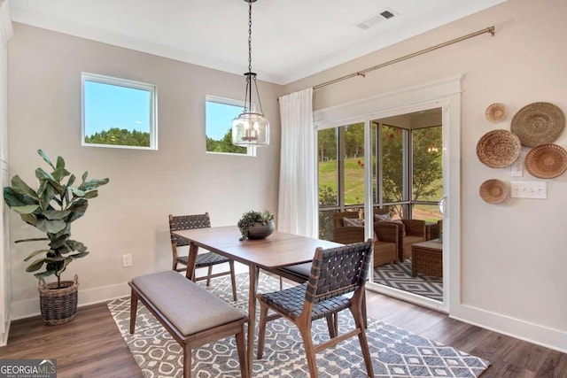 dining area with ornamental molding, a healthy amount of sunlight, and dark hardwood / wood-style flooring