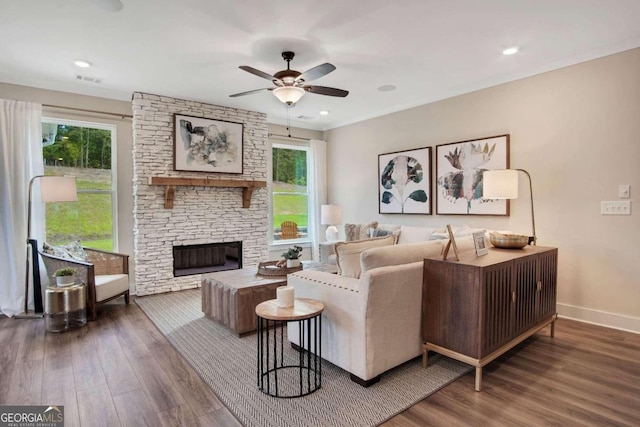 living room featuring hardwood / wood-style floors, a stone fireplace, and ceiling fan