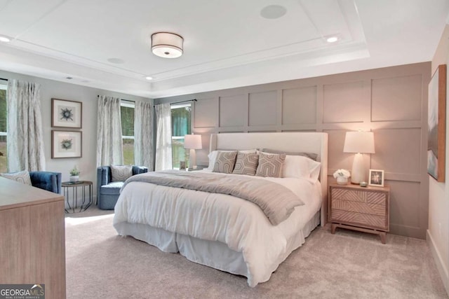 bedroom with light carpet, a raised ceiling, and ornamental molding