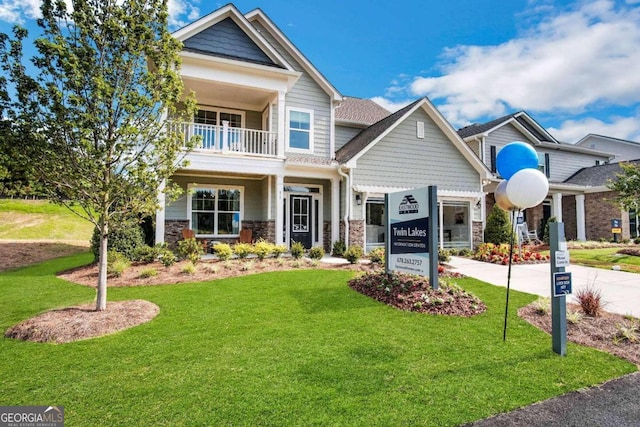 craftsman inspired home featuring a balcony and a front lawn