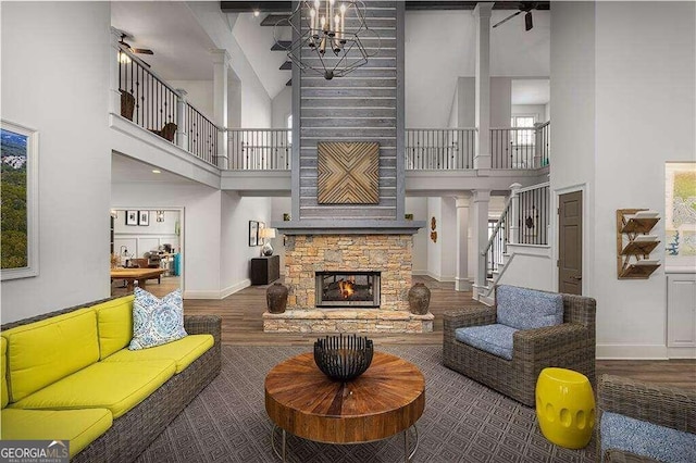 living room featuring beamed ceiling, a stone fireplace, wood-type flooring, and high vaulted ceiling