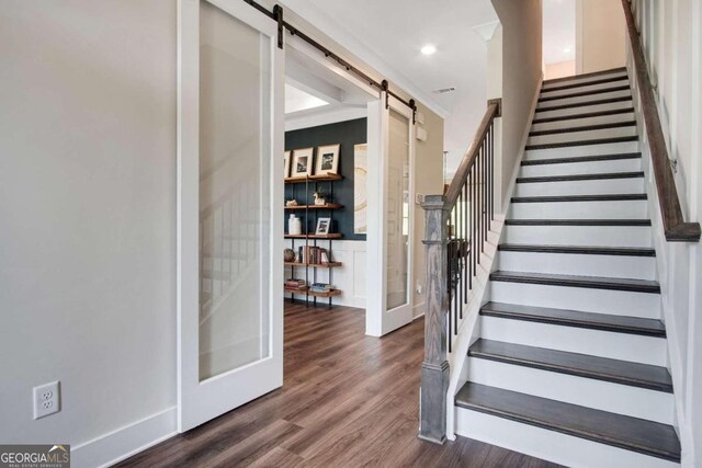 staircase featuring a barn door and wood-type flooring