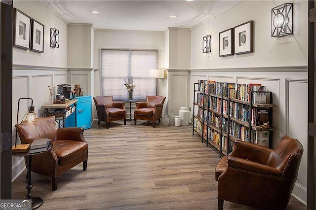 living area featuring wood-type flooring and ornamental molding