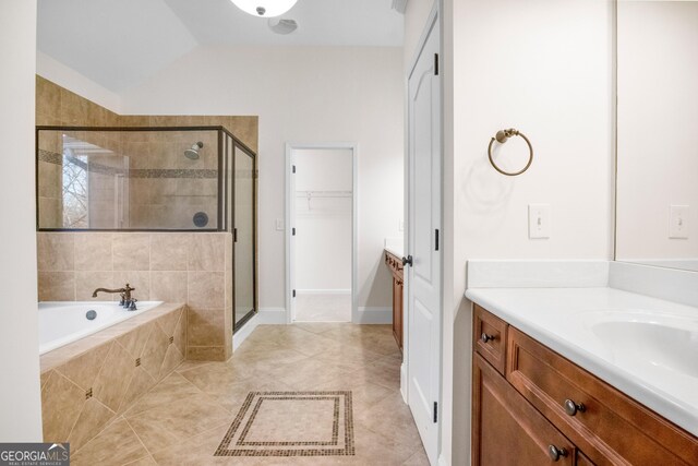 bathroom featuring tile patterned flooring, shower with separate bathtub, vaulted ceiling, and vanity