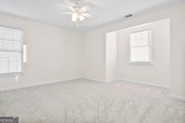 spare room with a healthy amount of sunlight, light carpet, and ceiling fan