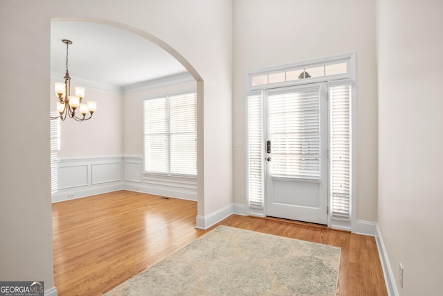 entrance foyer with ornamental molding, a chandelier, and light wood-type flooring