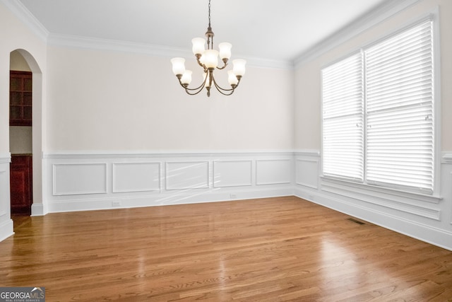 unfurnished room featuring crown molding, wood-type flooring, and a notable chandelier