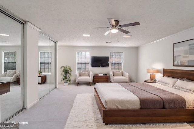 bedroom with ceiling fan, light colored carpet, a textured ceiling, and two closets