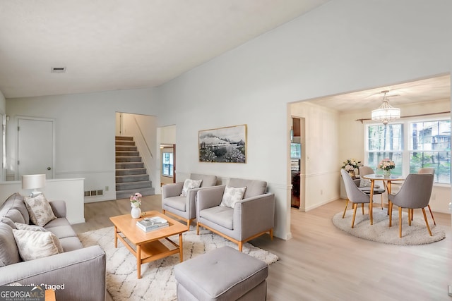 living room featuring lofted ceiling, light hardwood / wood-style floors, and a chandelier