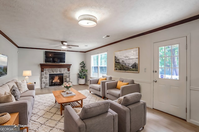 living room with ornamental molding, a fireplace, light hardwood / wood-style flooring, and a textured ceiling