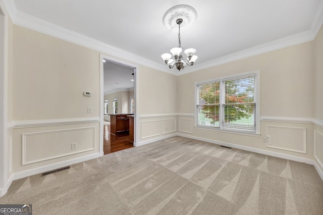 carpeted spare room with a notable chandelier and ornamental molding